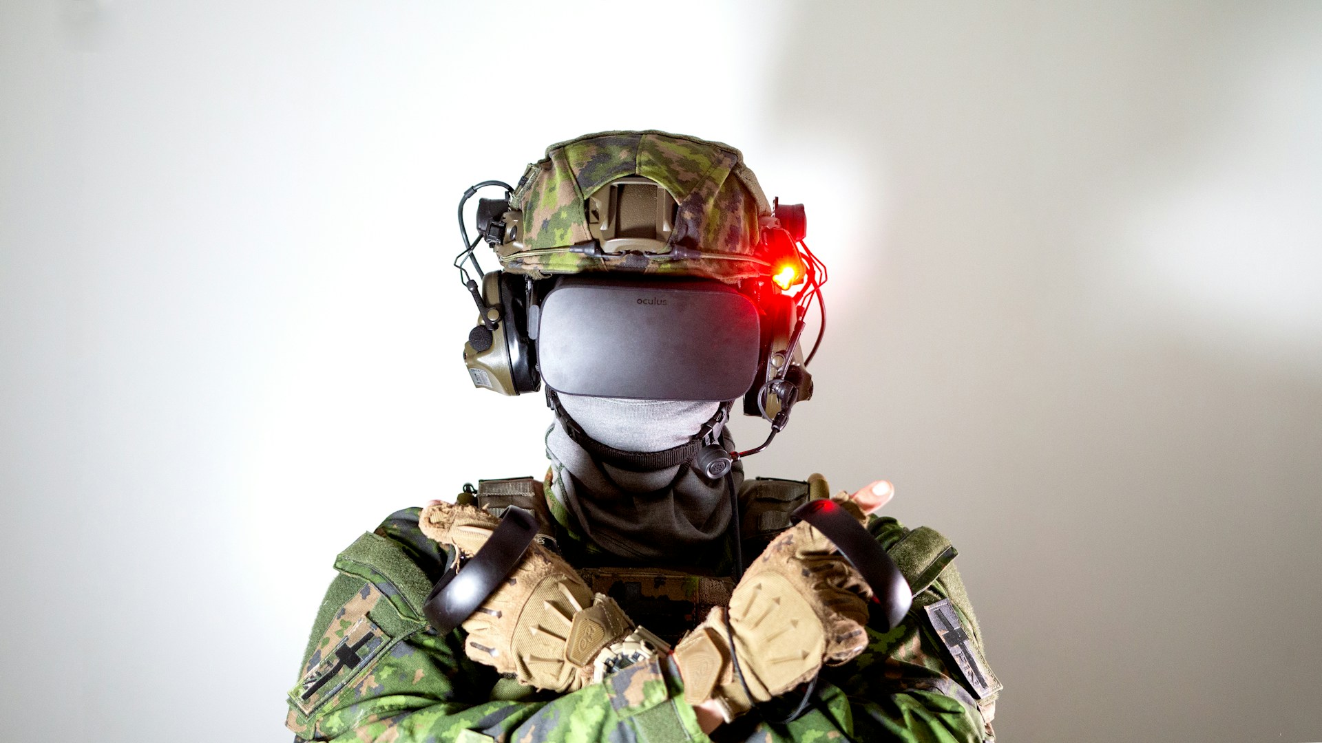 Close-up of a figure wearing camouflage military gear, helmet, and a VR headset with an illuminated red light for advanced training or simulation.