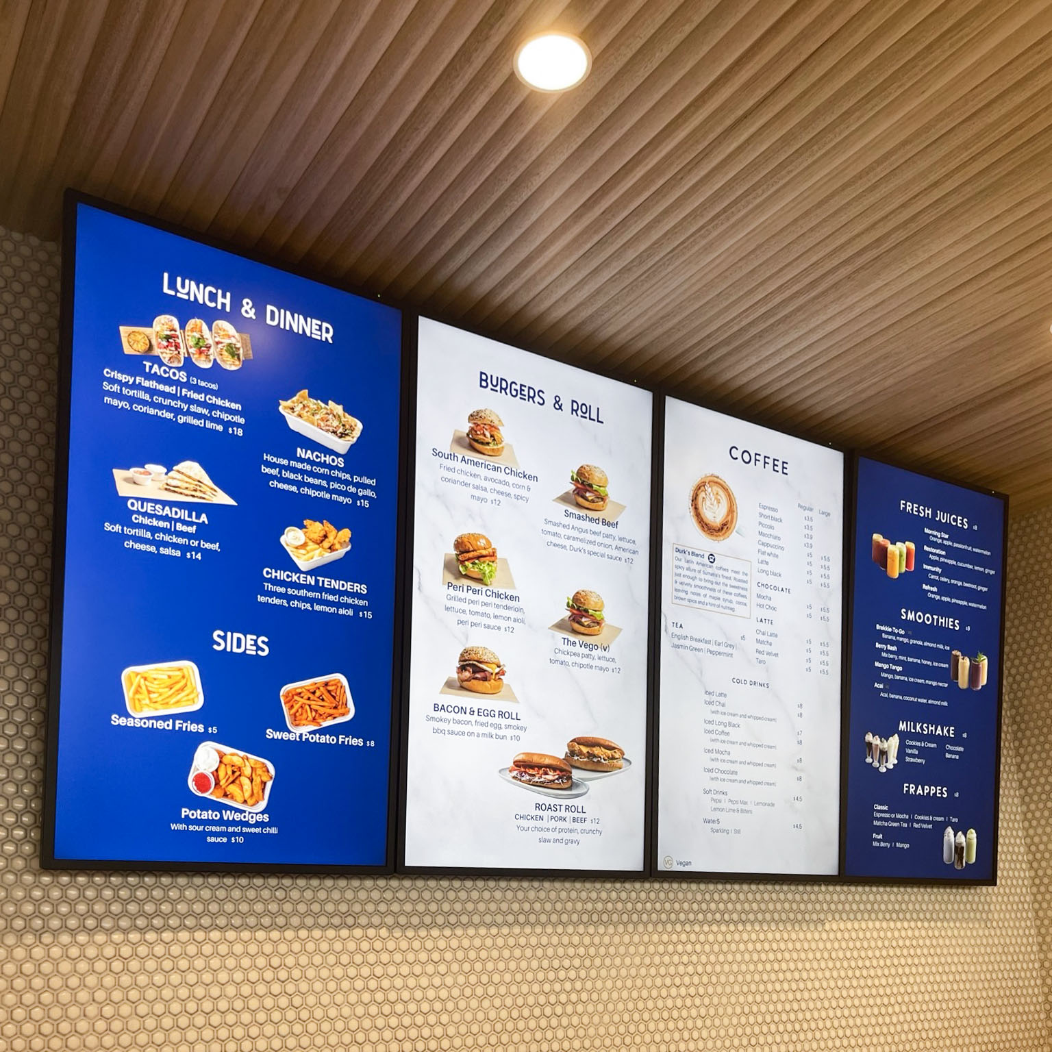 A series of three digital screens installed vertically to display a cafe and eatery menu. The menu features food categories like Lunch & Times, Bites & Roll, and Sweet Treat.